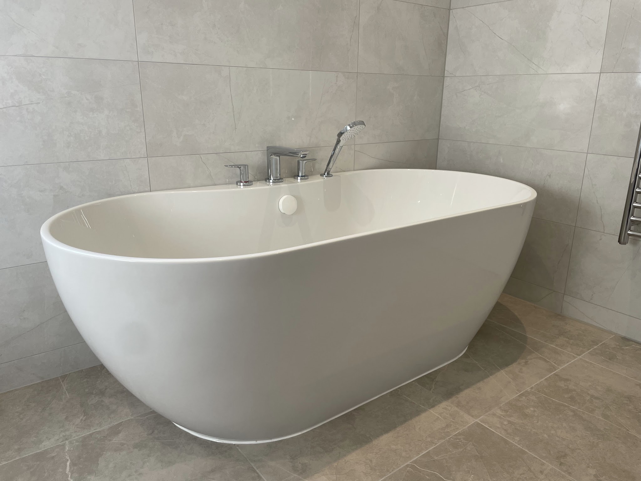 Freestanding bath against grey tiles