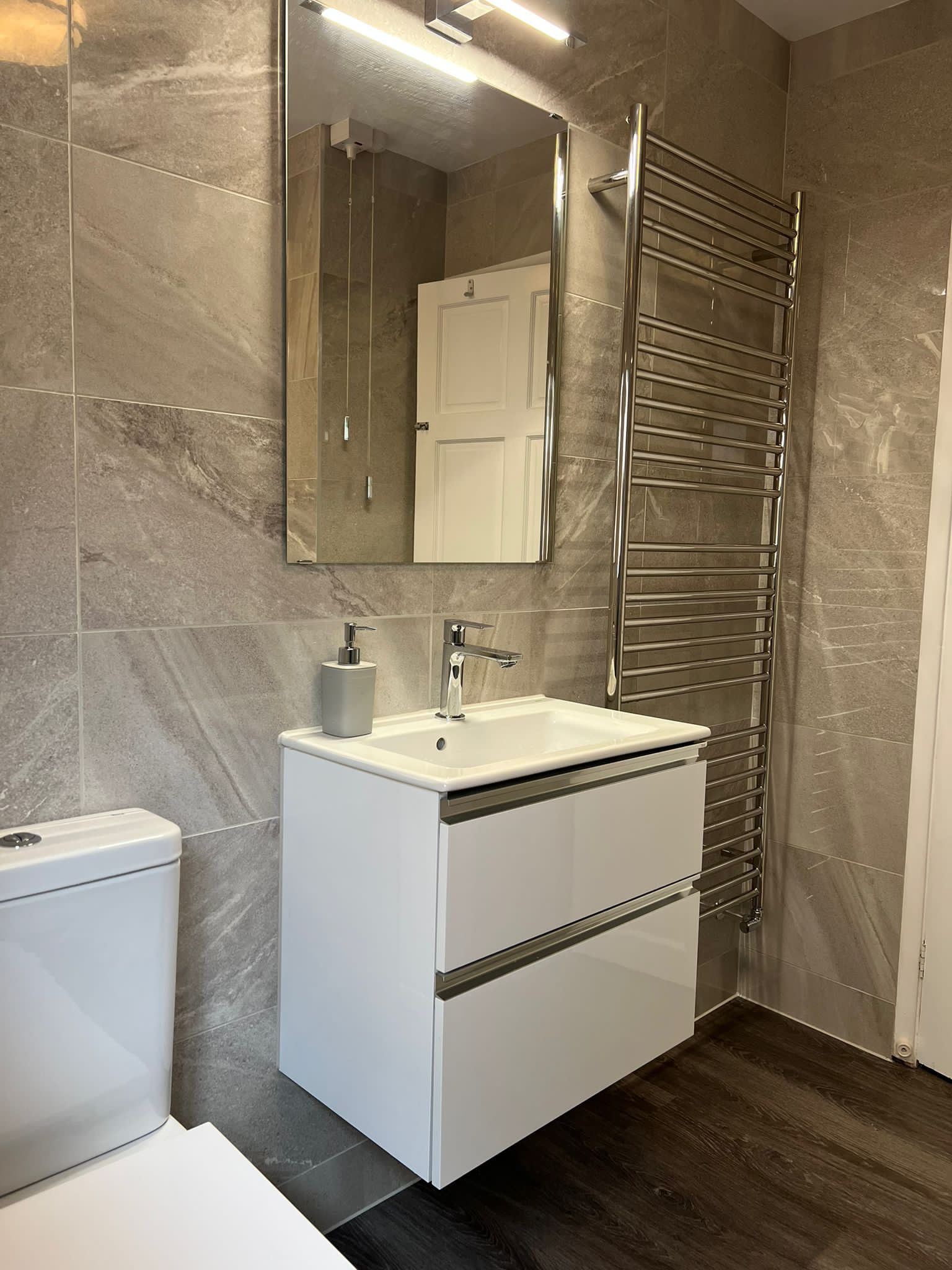 White wall-hung vanity unit and chrome towel rail