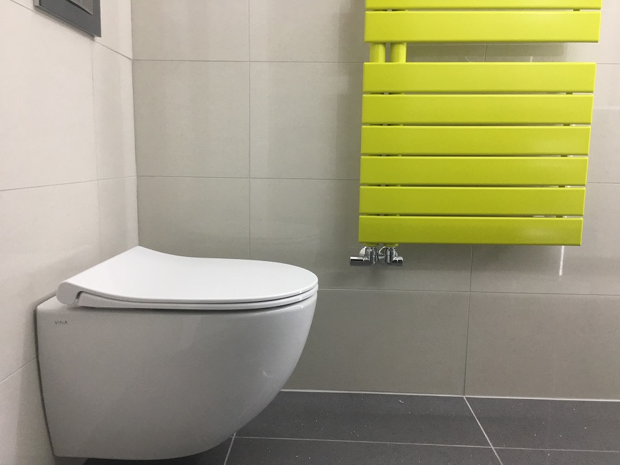 Wall-hung toilet beside a lime green towel radiator