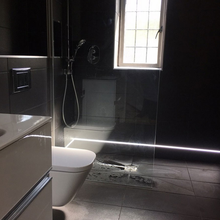 Black wetroom with an LED strip lighting the floor